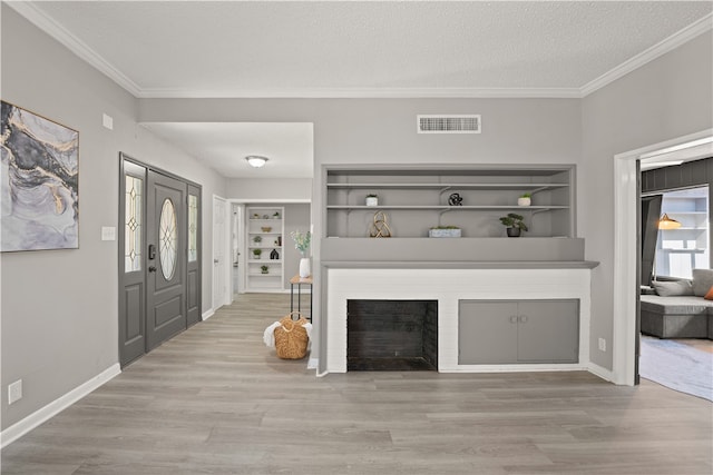 unfurnished living room with a brick fireplace, ornamental molding, a textured ceiling, and light hardwood / wood-style flooring