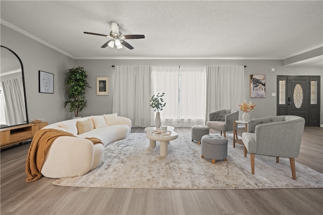 living room featuring a textured ceiling, hardwood / wood-style flooring, ceiling fan, and ornamental molding