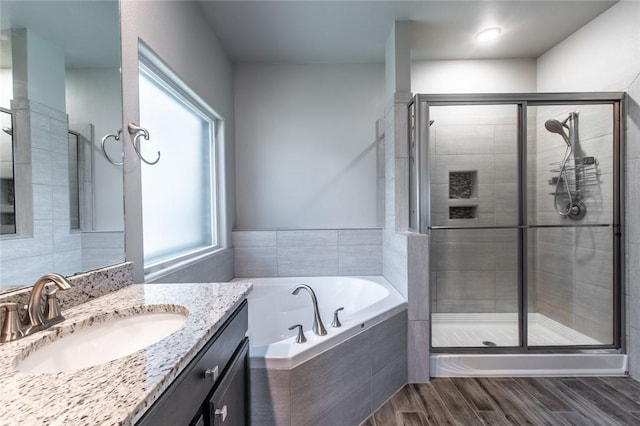 full bathroom with wood finished floors, a garden tub, a stall shower, and vanity