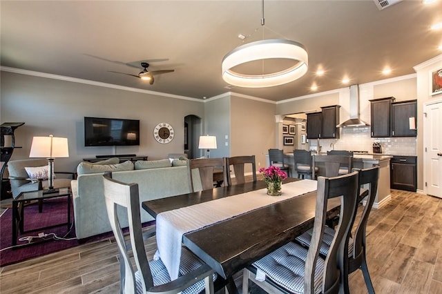 dining space featuring crown molding, wood finished floors, and ceiling fan