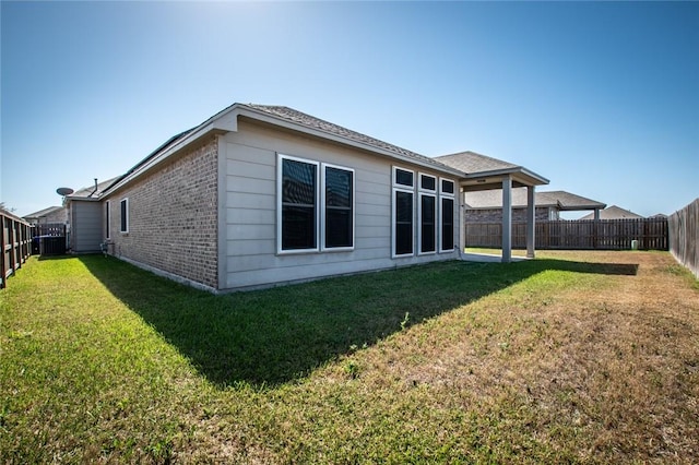 rear view of house with a lawn and a fenced backyard