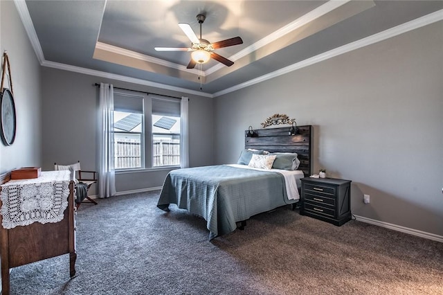 bedroom with ornamental molding, a ceiling fan, a tray ceiling, dark colored carpet, and baseboards