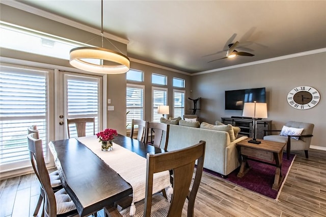 dining space with light wood-style flooring, a ceiling fan, baseboards, and ornamental molding