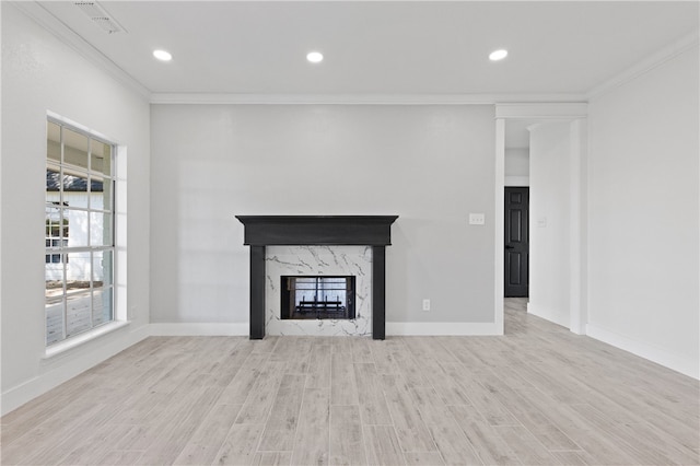 unfurnished living room with light hardwood / wood-style floors, a premium fireplace, and crown molding