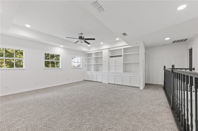 spare room featuring ceiling fan, plenty of natural light, carpet flooring, and a raised ceiling