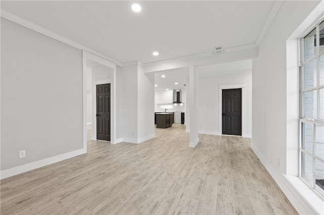 empty room featuring light hardwood / wood-style flooring, a healthy amount of sunlight, and crown molding