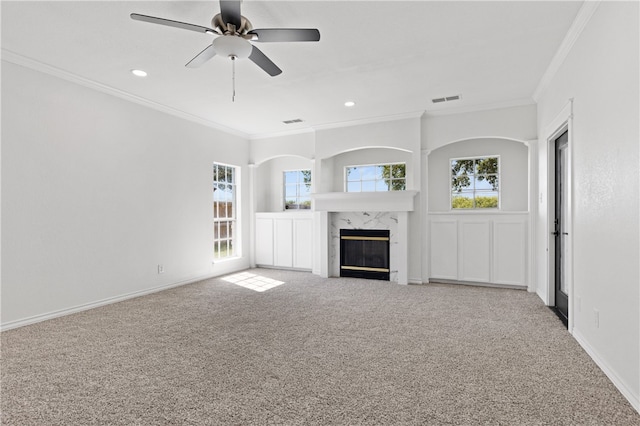 unfurnished living room featuring a premium fireplace, light carpet, crown molding, and ceiling fan