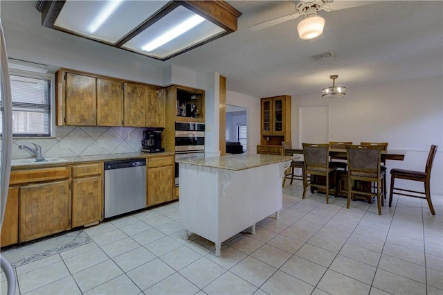 2413 Cricket Hollow St, Corpus Christi, TX 78414 - kitchen featuring appliances with stainless steel finishes, brown cabinetry, a sink, and tasteful backsplash