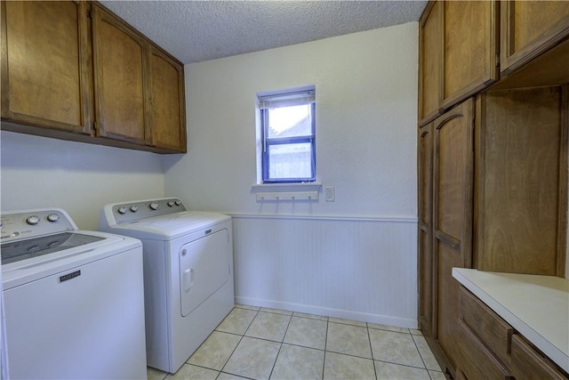 2413 Cricket Hollow St, Corpus Christi, TX 78414 - washroom with washer and dryer, cabinet space, a wainscoted wall, a textured ceiling, and light tile patterned floors