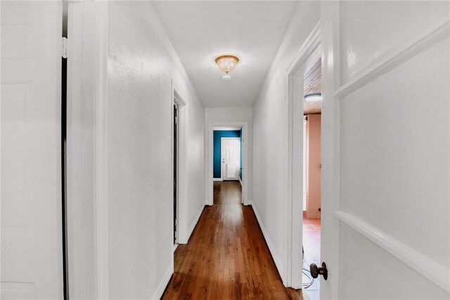 hallway featuring baseboards and hardwood / wood-style flooring