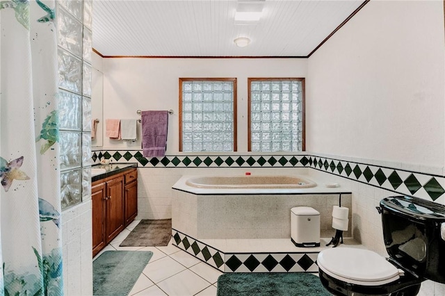 bathroom with a garden tub, toilet, tile walls, a wainscoted wall, and tile patterned floors