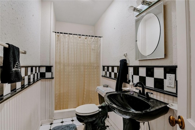 bathroom featuring tile patterned floors, a textured wall, toilet, and a shower with shower curtain
