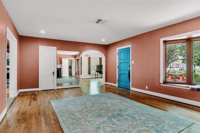 foyer entrance with baseboards, visible vents, and wood finished floors