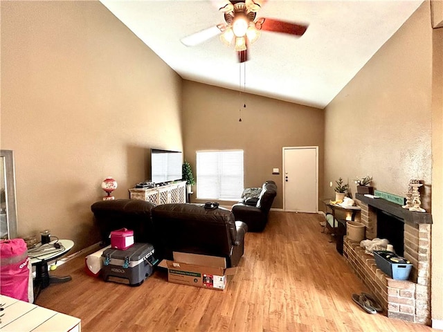 living room with wood finished floors, high vaulted ceiling, ceiling fan, and a fireplace