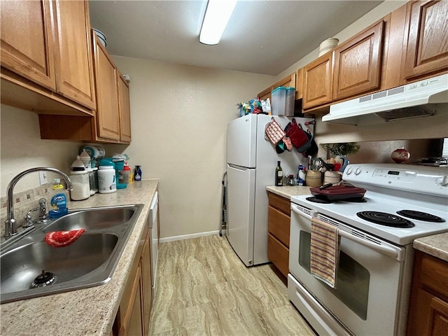 kitchen with under cabinet range hood, brown cabinets, white appliances, and a sink