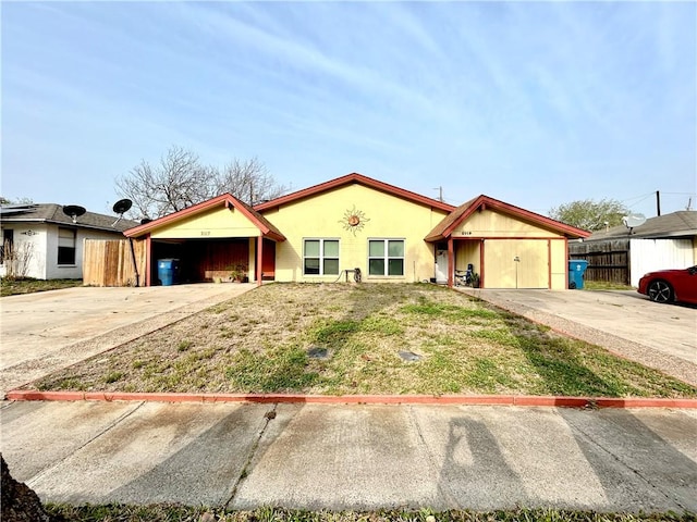 view of front of home with stucco siding, concrete driveway, and fence