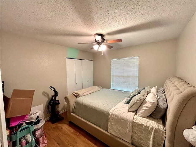 bedroom with a ceiling fan, wood finished floors, a closet, and a textured ceiling