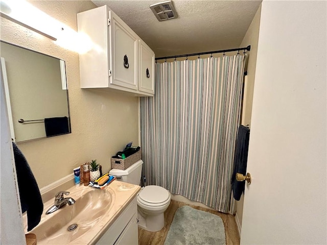 full bathroom with vanity, a shower with shower curtain, visible vents, a textured ceiling, and toilet