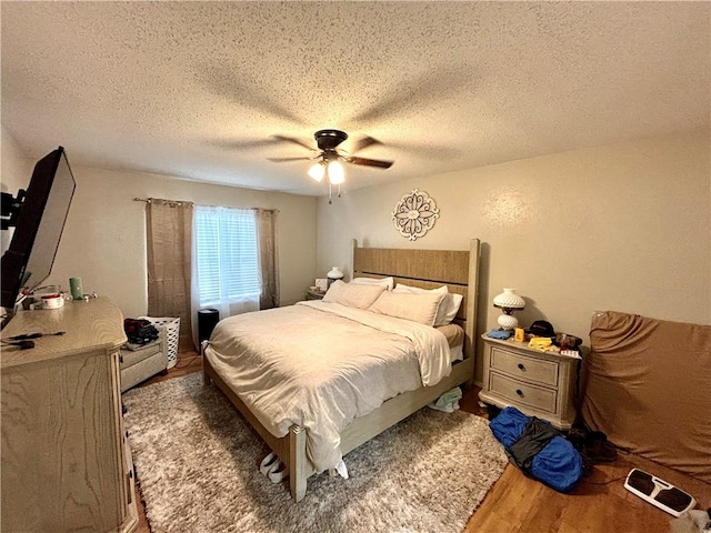 bedroom featuring a ceiling fan, wood finished floors, and a textured ceiling