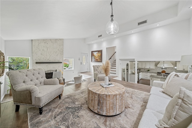 living room with a high ceiling, hardwood / wood-style floors, a healthy amount of sunlight, and a fireplace