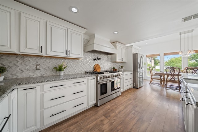 kitchen featuring stainless steel appliances, dark hardwood / wood-style flooring, pendant lighting, white cabinetry, and premium range hood