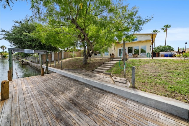 view of dock with a water view and a yard