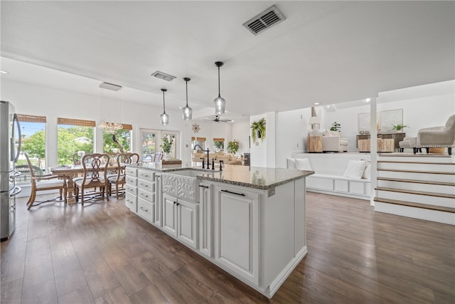 kitchen featuring a center island with sink, white cabinets, dark hardwood / wood-style floors, ceiling fan, and decorative light fixtures