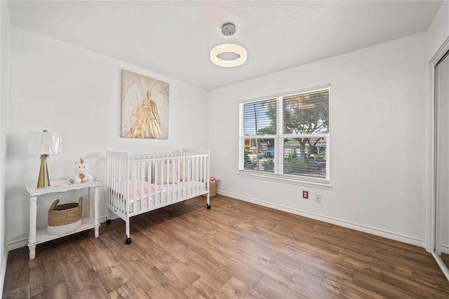 bedroom featuring wood-type flooring and a nursery area