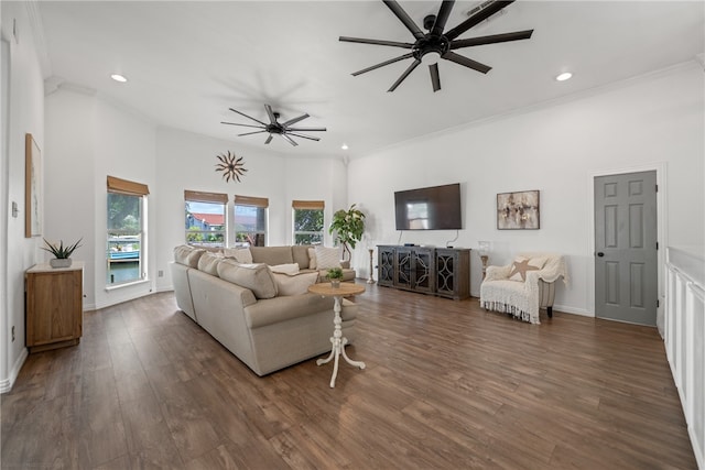 living room with dark wood-type flooring, ceiling fan, ornamental molding, and a towering ceiling