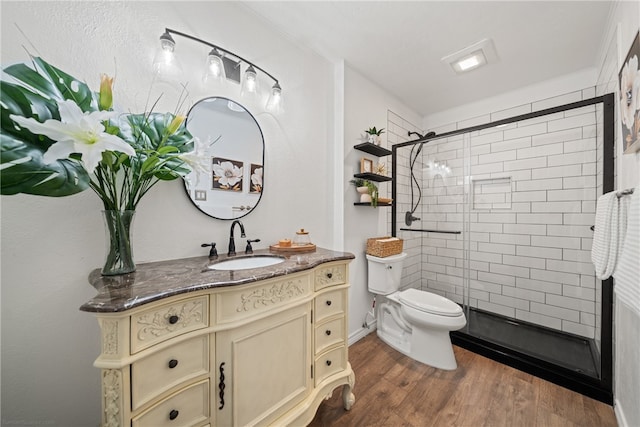 bathroom featuring wood-type flooring, toilet, vanity, crown molding, and a shower with shower door