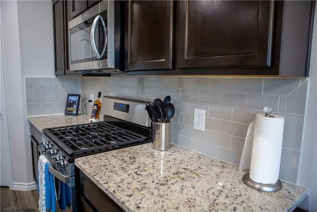 2682 Excelsior Blvd, Corpus Christi, TX 78415 - kitchen with stainless steel appliances, dark brown cabinets, decorative backsplash, and light stone countertops