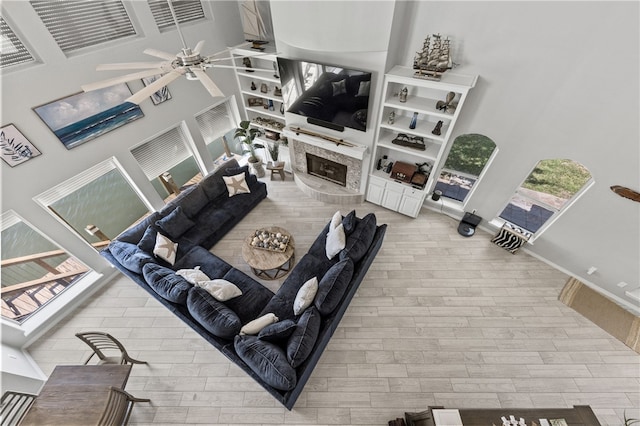 living room with a towering ceiling, ceiling fan, and wood-type flooring