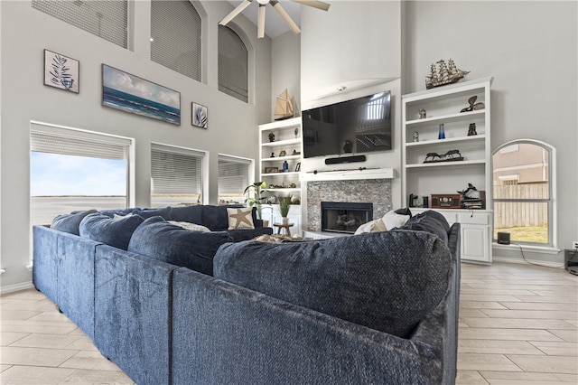 living room with light wood-type flooring, a wealth of natural light, ceiling fan, and a high ceiling