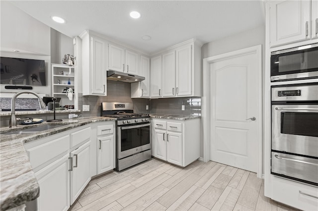 kitchen featuring stainless steel appliances, white cabinets, sink, backsplash, and light stone countertops