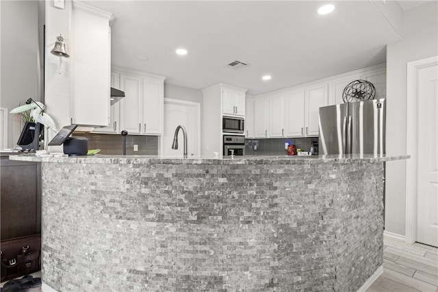 kitchen featuring backsplash, white cabinetry, appliances with stainless steel finishes, and light stone counters