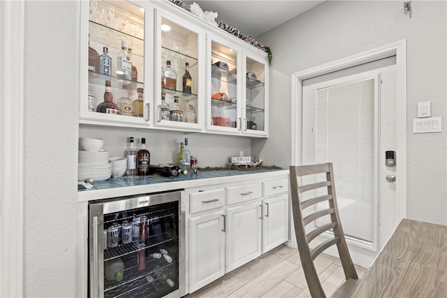 bar with white cabinetry, wine cooler, and light hardwood / wood-style flooring