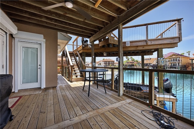 deck with ceiling fan and a water view