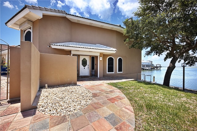 view of front of property featuring a water view, a front yard, and a patio