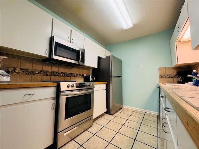 kitchen featuring backsplash, stainless steel appliances, sink, white cabinetry, and light tile patterned flooring