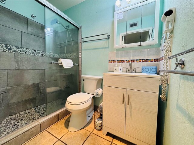 bathroom with tile patterned floors, vanity, an enclosed shower, and toilet