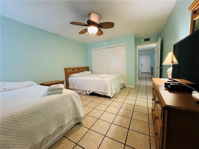 bedroom with ceiling fan, light tile patterned flooring, and a closet