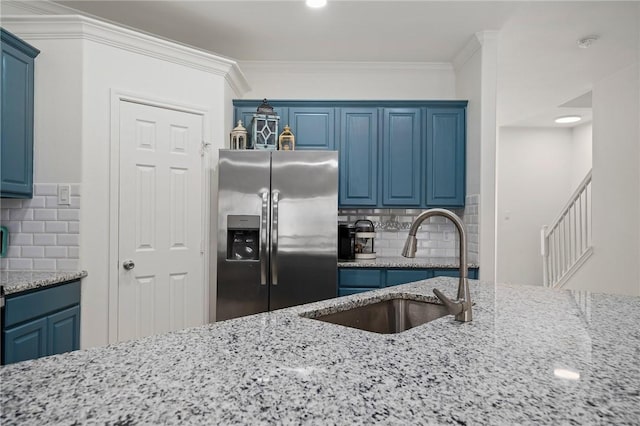 kitchen with sink, decorative backsplash, blue cabinetry, and stainless steel refrigerator with ice dispenser