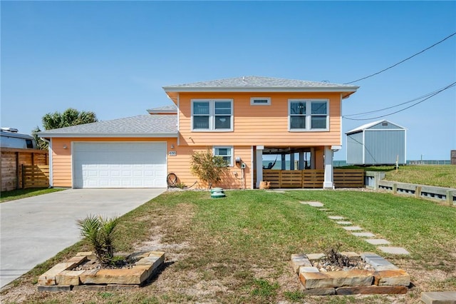 view of front of house with a front yard, fence, roof with shingles, an attached garage, and concrete driveway