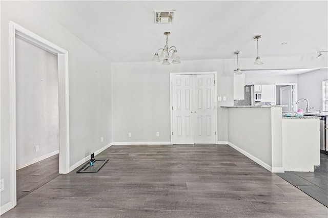 unfurnished dining area with an inviting chandelier, baseboards, dark wood-style floors, and visible vents