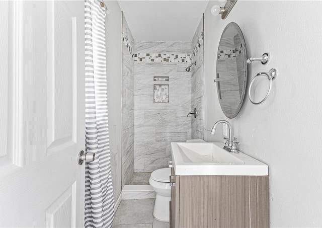 bathroom with vanity, tile patterned flooring, a tile shower, and toilet