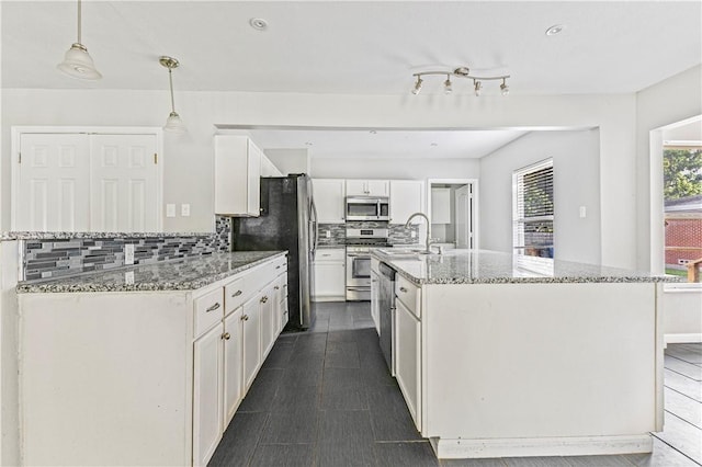 kitchen featuring tasteful backsplash, light stone countertops, a sink, stainless steel appliances, and white cabinetry