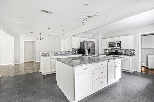 kitchen featuring light stone countertops, a sink, stainless steel appliances, tasteful backsplash, and visible vents