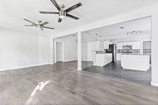 unfurnished living room featuring ceiling fan, baseboards, and dark wood-type flooring