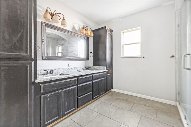full bath featuring double vanity, a sink, baseboards, and tile patterned flooring