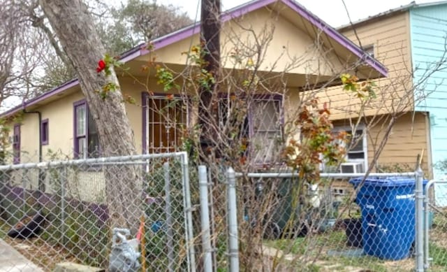 view of side of home with fence, a gate, and stucco siding